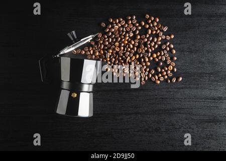 Caffè in grani e macchina per caffè bialetti. Vaso Moka su tavolo nero. Vista dall'alto. Foto Stock