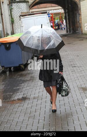 Donna che combatte contro la pioggia a Nile Court, Ayr, Ayrshire, Scozia, Regno Unito Foto Stock