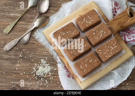 Dolci al cioccolato con frutta secca e semi di sesamo su tavola di legno su tavola di legno, stile rustico. Cibo sano fatto in casa Foto Stock