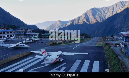 Lukla, Nepal - 11/28/2019: Scena affollata con aerei pronti per il decollo sulla pista dell'aeroporto di Tenzing-Hillary, uno degli aeroporti più pericolosi. Foto Stock