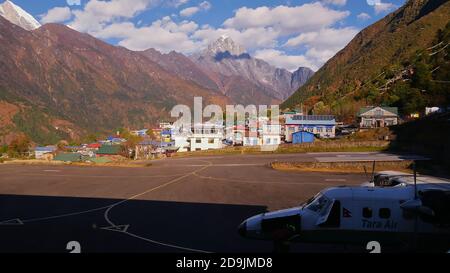 Lukla, Nepal - 11/28/2019: Aereo Tara Air pronto per l'imbarco di fronte al terminal dell'aeroporto Tenzing-Hillary con pista, villaggio Sherpa e Himalaya. Foto Stock