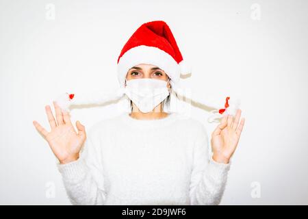 Giovane donna caucasica isolata su sfondo bianco mostra tenendo le sue false trecce bianche. Fiocco di neve e concetto di Babbo Natale. Foto Stock