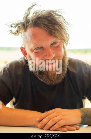 Ritratto esterno di un giovane bel ragazzo sorridente zenzero con barba. Primo piano ritratto di un giovane felice sorridente Foto Stock