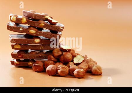 pila di pezzi di cioccolato al latte e nocciole su sfondo marrone con spazio per la copia Foto Stock
