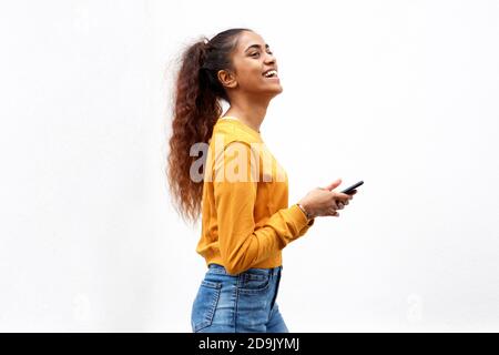 Ritratto di lato ragazza indiana felice tenendo cellulare da bianco sfondo Foto Stock