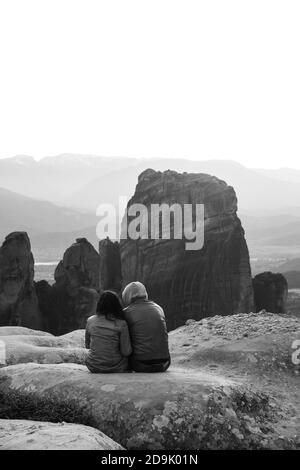 Coppia seduto godendo la vista da una delle rocce di Meteora. Sito patrimonio dell'umanità dell'UNESCO Meteora, Grecia Foto Stock