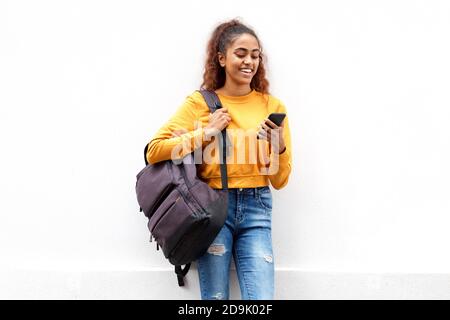 Ritratto di giovane donna indiana sorridente con telefono cellulare e. sacchetto con fondo bianco isolato Foto Stock