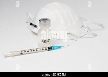 Flaconcino con vaccino Covid-19, siringa e ago e maschera facciale N95 isolato su fondo bianco. Concetto di pandemia di coronavirus, immunizzazione Foto Stock