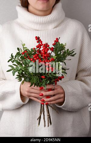 Donna che tiene le bacche di agrifoglio rosse di Natale, vista ravvicinata Foto Stock