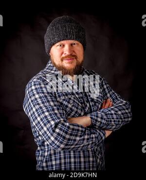 Uomo con bearded solido in un ritratto di cappellino di lana su nero sfondo Foto Stock