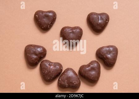 Cuori di pan di zenzero ricoperti di cioccolato tedesco su sfondo colorato light.brown. Pan di zenzero ricoperto di cioccolato. Faccia con il cibo. Deserto di Natale, Foto Stock