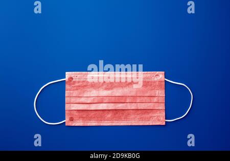 Maschera medica, maschera protettiva medica su sfondo blu. Maschera chirurgica monouso per il viso che copre bocca e naso. Concetto sanitario e medico. Foto Stock