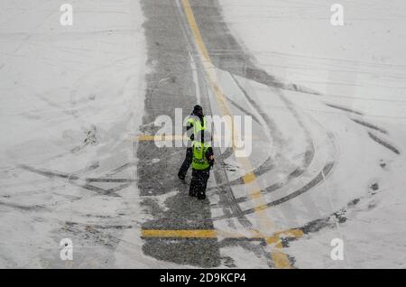 Lavoratori dell'aeroporto che hanno una conversazione mentre attendono l'aereo in cattivo tempo invernale con un sacco di neve. Aeroporto JFK, New York, Stati Uniti Foto Stock