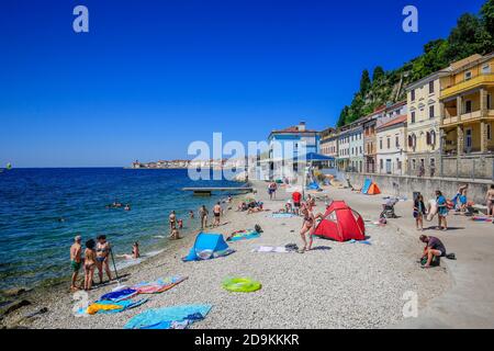 Piran, Istria, Slovenia - vita da spiaggia sulla spiaggia della città Fornace nella città portuale di Piran sul Mediterraneo. Foto Stock