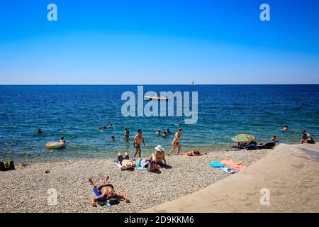 Piran, Istria, Slovenia - vita da spiaggia sulla spiaggia della città Fornace nella città portuale di Piran sul Mediterraneo. Foto Stock
