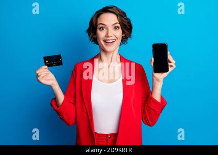 Ritratto di attraente donna allegra che dimostra la scheda di dispositivo wireless trasferimento pay pass dell'app web isolato su un colore blu brillante sfondo Foto Stock