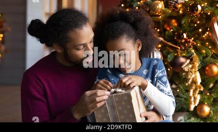 Primo piano padre afroamericano e figlia disimballaggio regalo di Natale Foto Stock