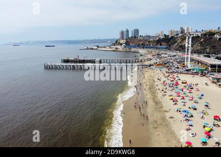 Vista aerea di Playa Caleta Portales e le persone che si rilassano sulla spiaggia vicino all'oceano. Molo dei pescatori e vista sulla città. Valparaiso, Cile. Foto Stock