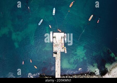 Vista aerea del molo dei pescatori con molte barche da pesca parcheggiate in un porto. Colori verde e blu dell'oceano Pacifico. Vista dall'alto Foto Stock
