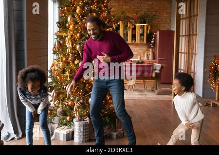 Il padre afroamericano si è divertito molto con i bambini che si divertono a Natale Foto Stock