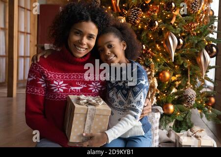 La testa ha girato sorridendo la donna afroamericana e la figlia che festeggia il Natale Foto Stock