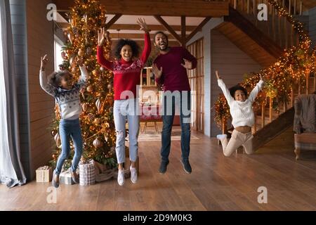 La famiglia afroamericana si è divertita molto con i bambini che saltano, godendosi le vacanze invernali Foto Stock