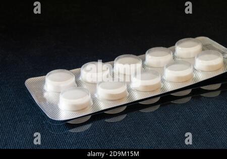 Le pillole mediche in imballaggio su sfondo nero. Imballaggio con tablet sul tavolo con riflessione Foto Stock