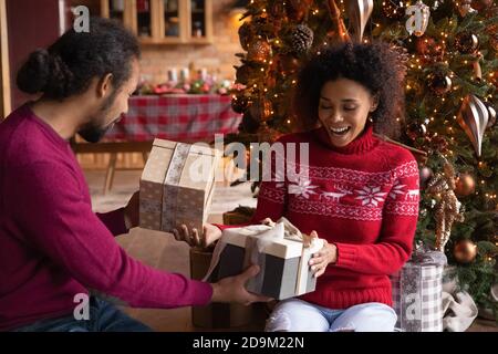 L'uomo e la donna afro-americana si sono molto gioiti dando regali di Natale Foto Stock