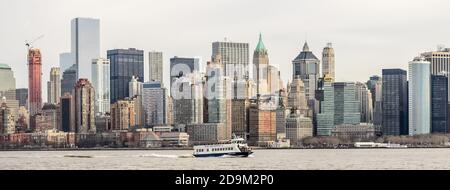 Una nave da crociera sul canale navigabile di NY con torri e grattacieli in background, Lower Manhattan, New York City, USA Foto Stock