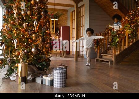 I bambini afroamericani sono stati molto contentissimi e corrono al piano di sotto la mattina di Natale Foto Stock