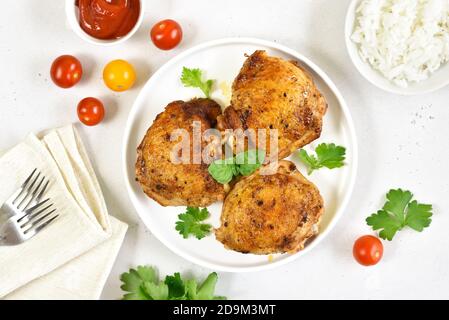 Cosce di pollo fritte in piatto su fondo di pietra bianca. Vista dall'alto, disposizione piatta Foto Stock