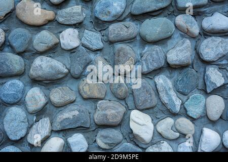 Struttura muraria in pietra, strada fatta di piccole pietre rotonde e di mare Foto Stock