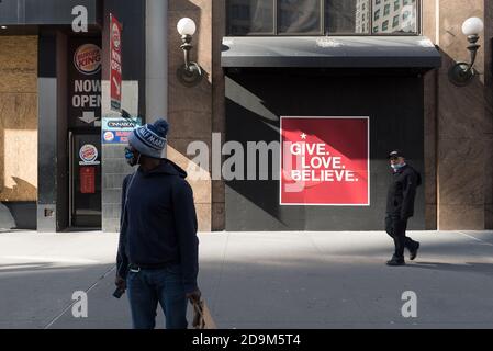 Un uomo che indossa una maschera si trova di fronte a una delle finestre di Macy's. Foto Stock