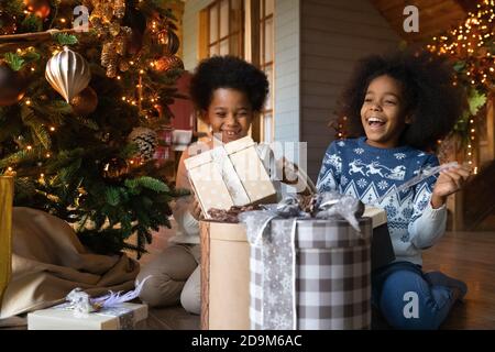 Primo piano su capretti afroamericani overjoyed che disimballano i regali di Natale Foto Stock