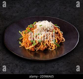 Bolognese di pasta italiana. Deliziosi spaghetti bolognesi serviti su un piatto nero Foto Stock