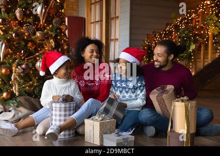 La famiglia afroamericana si è divertita molto con i bambini che disimballano i regali di Natale Foto Stock