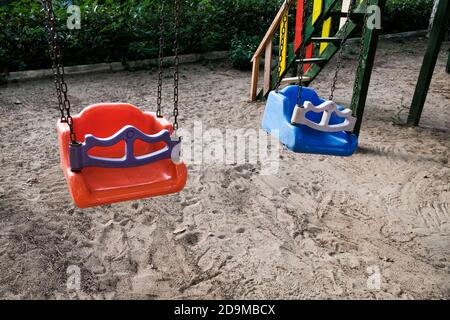 Altalene vuote sul parco giochi per bambini. Swing colorato incustodito durante l'epidemia di coronavirus. Chiuso per bambini in pandemia. Nessuno che gioca Foto Stock