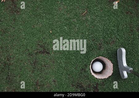 Giocare a mini golf su erba verde artificiale all'aperto. Definizione di obiettivi e concetto di stile di vita vincente. Divertimento per le vacanze estive. Mettere Foto Stock