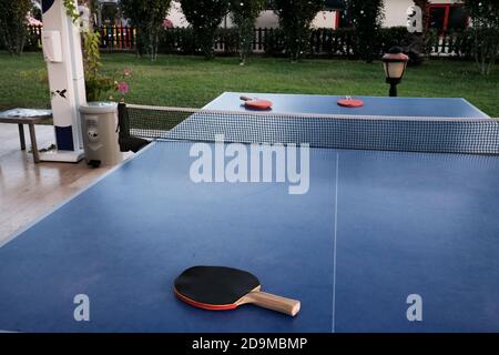 Belek, Turchia - Ottobre 2020: Nessuno gioca a ping pong all'esterno. Hotel sopravvissuti durante la quarantena. Tre racchette su un tavolo blu, prato verde Foto Stock