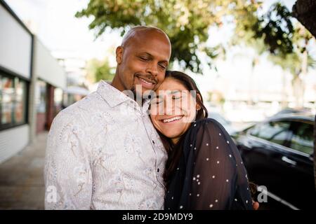 La coppia multiracial Late Forties si è abbracciata sul marciapiede di San Diego Foto Stock