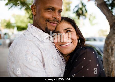 La coppia multiracial Late Forties si è abbracciata sul marciapiede di San Diego Foto Stock