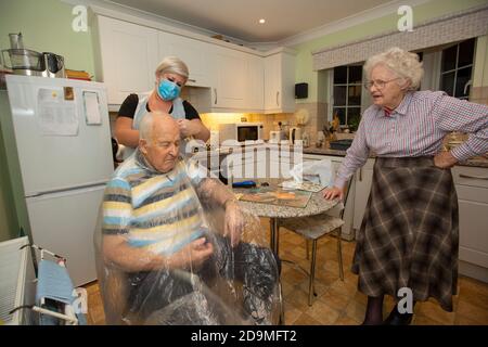 Coppie anziane negli anni 80 a casa loro che hanno il tè servito da un assistente di assistenza sociale durante il blocco pandemico del coronavirus, Inghilterra, Regno Unito Foto Stock