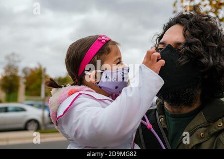 Bambina in costume halloween con papà che indossa la faccia protettiva maschera Foto Stock