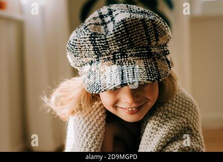 ritratto di una giovane ragazza con un cappello su giocosamente sorridendo a casa Foto Stock