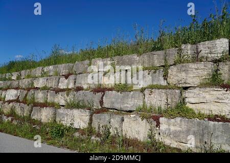 Germania, Baviera, alta Baviera, distretto di Altötting, parete argentata, rinforzo pendenza, blocchi di granito, surcresciuto, accanto ad una strada Foto Stock