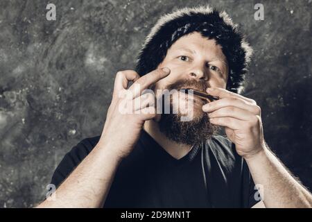 Uomo maturo in pelliccia cappello che gioca ebrei arpa ritratto studio Foto Stock