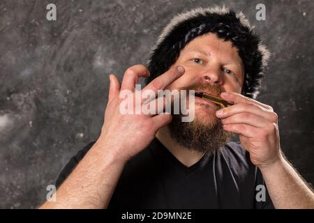 Uomo maturo in pelliccia cappello che gioca ebrei arpa ritratto studio Foto Stock