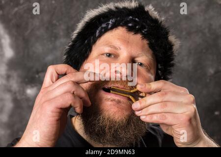 Uomo maturo in pelliccia cappello che gioca ebrei arpa ritratto studio Foto Stock