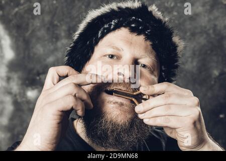 Uomo maturo in pelliccia cappello che gioca ebrei arpa ritratto studio Foto Stock