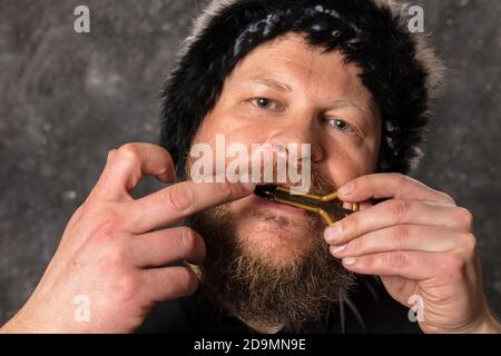 Uomo maturo in pelliccia cappello che gioca ebrei arpa ritratto studio Foto Stock